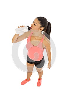 Fit latin sport woman in fitness clothes drinking water tired during training workout