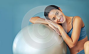 The fit life. a sporty young woman leaning against a pilates ball.