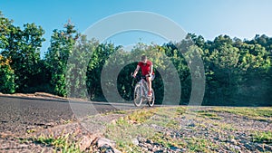 Fit male biker cyclist riding his bike cycle on an asphalt road at sunset