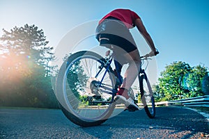 Fit male biker cyclist riding his bike cycle on an asphalt road at sunset