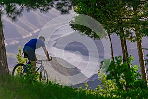 FIt male Cyclist is speeding up his bicycle downhill while enjoying the amazing mountain dirt road