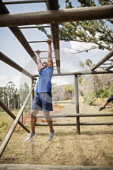 Fit man climbing monkey bars during obstacle course