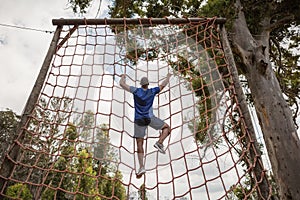 Fit man climbing a net during obstacle course