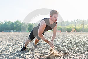 Fit man doing clapping push-ups during training exercise workout on beach in summer.