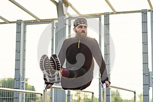 Fit man doing triceps dips on parallel bars at park exercising outdoors