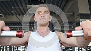 Fit man doing push ups at machines in the gym