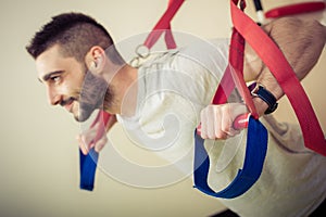 Fit man doing push ups training arms with fitness straps