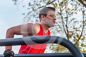 Fit man doing triceps dips on parallel bars at park exercising outdoors