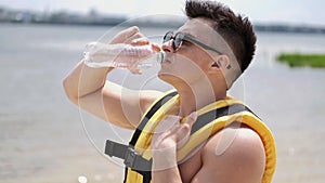 Fit man drinking water from a bottle outside at the beach