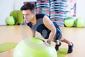 Fit man exercising with ball workout out arms Exercise training triceps and biceps doing push ups.