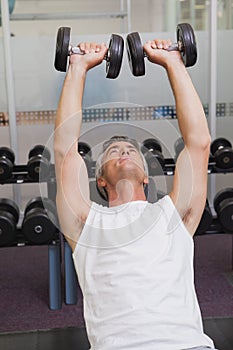 Fit man lifting dumbbells lying on the bench