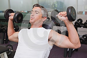 Fit man lifting dumbbells lying on the bench