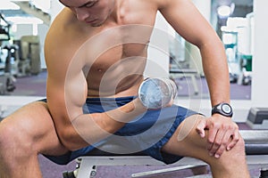 Fit man lifting dumbbells sitting on the bench