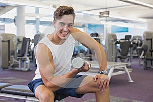 Fit man lifting dumbbells sitting on the bench