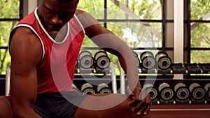 Fit man lifting dumbbells while sitting on the bench