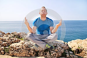 A fit man in the Lotus position on a seashore. Young fitness man doing yoga outdoors.