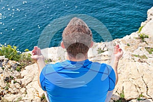 A fit man in the Lotus position on a seashore. Young fitness man doing yoga outdoors.