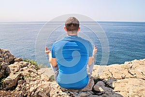 A fit man in the Lotus position on a seashore. Young fitness man doing yoga outdoors.
