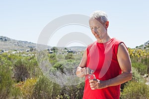 Fit man opening his water bottle on mountain trail