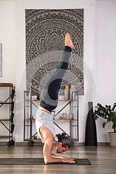 Fit man performing supported Handstand yoga at home