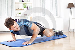 Fit Man Planking on Mat While Lifting One Leg photo