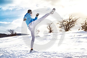 Fit man practicing a kick shot outdoor in snow. Fitness player training