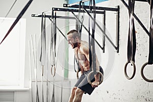 Fit man pulling up on gymnastic rings.