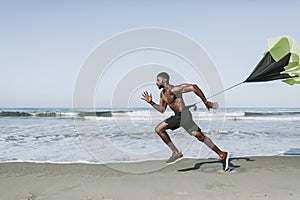 Fit man with a running parachute at the beach