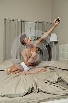 Fit man in take selfie in bed