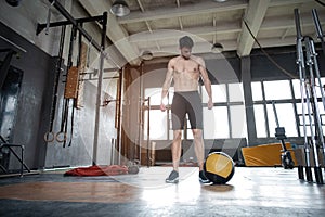 Fit man throwing medicine ball doing ball slam against gym floor or shoulder press upper body workout exercise