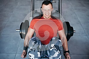 Fit man training legs on leg press machine in the gym