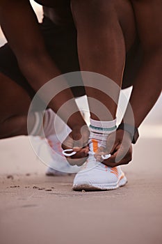 Fit man tying shoelaces. Closeup of hands of athlete getting ready to run. Closeup of fit man working out on the beach