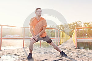 Fit man warming up doing lunges exercising during morning run.