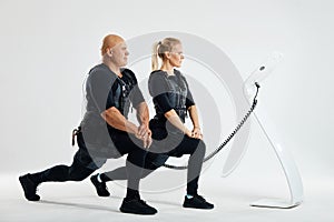 Fit man and woman stretching legs indoors doing forward lunge