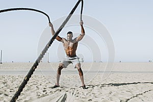 Fit man working out with battle ropes