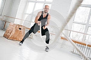 Fit man working out with battle ropes at hall