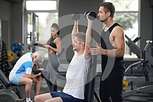 Fit man working out in gym with personal trainer.