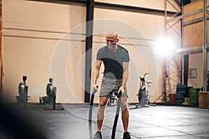 Fit man working out with ropes at the gym