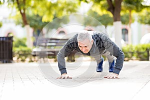 Fit mature man doing push ups in park