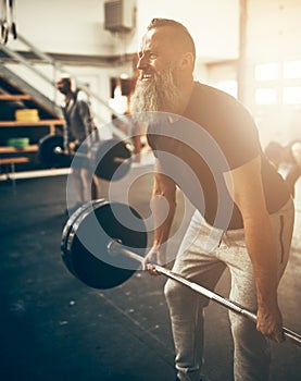 Fit mature man straining to lift weights in a gym photo