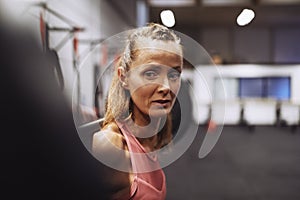 Fit mature woman doing barbell squats during a gym workout