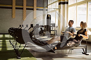 Man and woman training on rowing machines in gym together photo