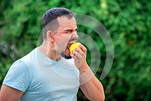 Fit middle-aged man biting yellow lemon. Portrait of handsome man eating lemon outdoors. Tough decisions and mental health concept