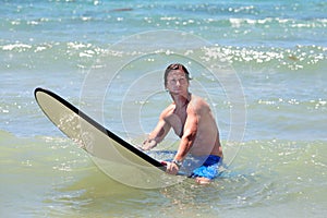 Fit middle aged man surfing on beach in summer