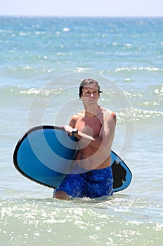 Fit middle aged man surfing on beach in summer