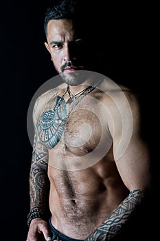 Fit model with tattoo art on skin. Bearded man with tattooed chest. Macho with bare torso. Sportsman or athlete with stylish