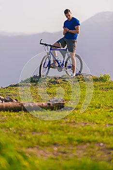 Fit mountain biker riding his bike through green grass on top of a mountain