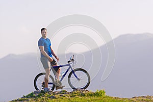 Fit mountain biker riding his bike through green grass on top of a mountain