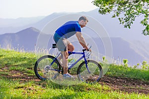 Fit mountain biker riding his bike through green grass on top of a mountain