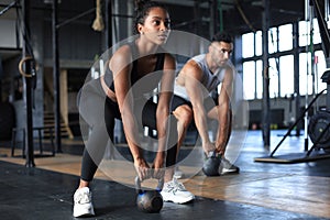 Fit and muscular couple focused on lifting a dumbbell during an exercise class in a gym photo